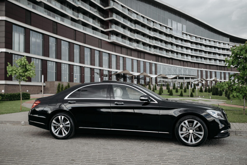 Black luxury sedan parked in front of a modern hotel.