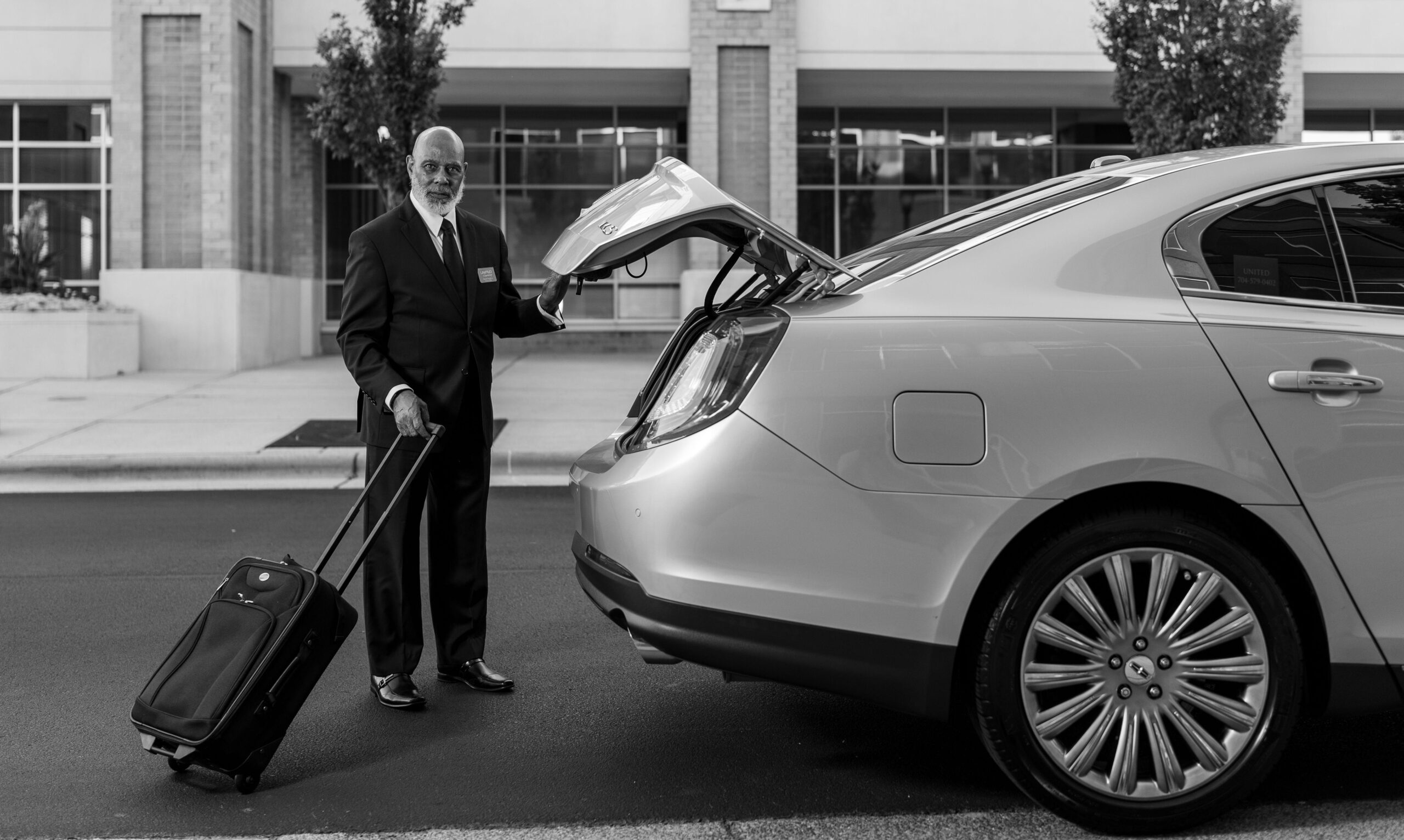 Professional chauffeur assisting clients with luggage, emphasising personalised service in executive travel